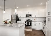 Thumbnail 49 of 61 - A modern kitchen with white cabinets and stainless steel appliances.