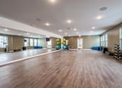Thumbnail 7 of 34 - A spacious room with wooden floors and exercise equipment.