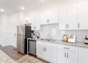 Thumbnail 19 of 34 - A kitchen with white cabinets and a stainless steel refrigerator.