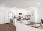 Thumbnail 21 of 34 - A modern kitchen with a dining table and chairs.