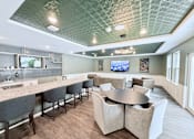 Thumbnail 1 of 34 - A modern dining room with a bar area and a television mounted on the wall.