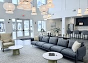 Thumbnail 3 of 34 - A grey couch with a white pillow is in the middle of a room with a grey carpet.
