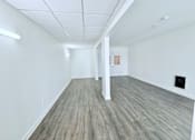 Thumbnail 37 of 61 - A spacious room with wooden flooring and white walls.