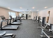 Thumbnail 8 of 34 - A spacious gym with treadmills, elliptical machines, and other exercise equipment.
