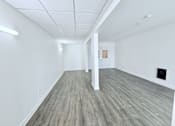 Thumbnail 23 of 34 - A spacious room with wooden flooring and white walls.