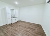 Thumbnail 34 of 61 - A room with a wooden floor and white walls.