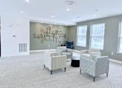 Thumbnail 16 of 34 - A modern waiting room with grey chairs and a large artwork on the wall.