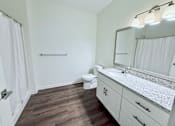 Thumbnail 51 of 61 - A bathroom with a toilet, sink, and mirror.
