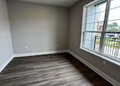 Thumbnail 32 of 34 - A room with a large window and wooden flooring.