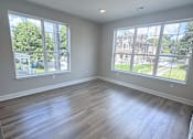 Thumbnail 7 of 34 - A room with two large windows and wooden flooring.