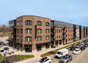 Thumbnail 47 of 48 - A street view of a row of modern buildings with cars parked in front.
