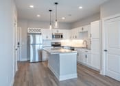 Thumbnail 17 of 34 - A modern kitchen with white cabinets and a central island.