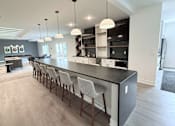 Thumbnail 4 of 61 - A modern kitchen with a long bar and chairs.