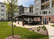 Thumbnail 16 of 61 - A gazebo sits in the middle of a grassy area in front of apartment buildings.