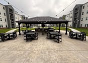 Thumbnail 17 of 61 - A gazebo with tables is surrounded by apartment buildings.