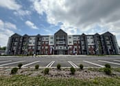 Thumbnail 58 of 61 - A large apartment complex with multiple buildings and a parking lot in front.
