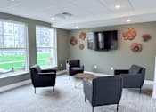 Thumbnail 41 of 61 - A room with grey chairs and a television on the wall.