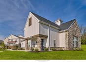 Thumbnail 3 of 6 - a white barn style home with a stone facade and a lawn