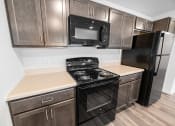 Thumbnail 22 of 26 - a kitchen with dark wood cabinets and black appliances  at Union at Wiley, Iowa, 52404