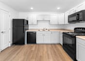 Thumbnail 15 of 22 - A kitchen with black appliances and white cabinets.at Union at North Crossing, Iowa