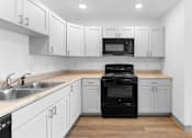 Thumbnail 16 of 22 - A black stove in a kitchen with white cabinets.at Union at North Crossing, Iowa, 50703