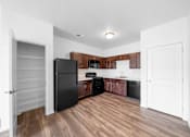 Thumbnail 9 of 21 - A kitchen with a black refrigerator and wooden cabinets. at Union at the Loop, Lawrence, Kansas
