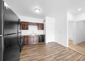 Thumbnail 8 of 21 - A black refrigerator is on the left in a kitchen with wooden floors. at Union at the Loop, Lawrence, KS