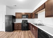 Thumbnail 7 of 21 - A kitchen with black appliances and brown cabinets. at Union at the Loop, Lawrence, KS, 66046