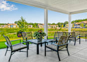 Thumbnail 5 of 26 - A patio with a table and chairs overlooking a residential area. at Union at Oak Grove, Howell, 48855