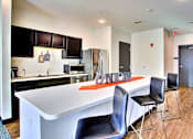 Thumbnail 9 of 13 - A modern kitchen with a white island and black chairs.at Union at Crescent, Bloomington, IN  