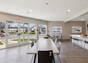 Thumbnail 6 of 27 - A large room with a long table and chairs, a kitchen area, and a view of the outside through the glass doors at Union at 16th, Indianapolis, IN