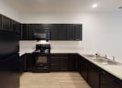 Thumbnail 3 of 18 - A black fridge and microwave in a kitchen with wooden floors at Union at 16th, Indiana