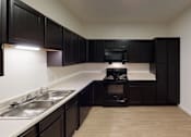Thumbnail 11 of 18 - A kitchen with black cabinets and a stove top oven.at Union at 16th, Indiana, 46222