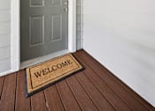Thumbnail 3 of 74 - A grey door with a wreath and a welcome mat on a wooden floor.