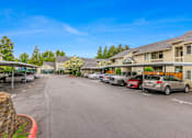 Thumbnail 2 of 36 - A parking lot with cars parked in front of apartment buildings.