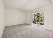 Thumbnail 5 of 74 - A large, empty room with a carpeted floor and a sliding glass door leading to a balcony.