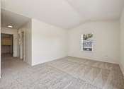 Thumbnail 37 of 74 - A sparsely furnished room with a carpeted floor and a window showing a house outside.