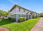 Thumbnail 4 of 35 - A grey house with a green lawn in front.