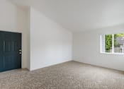Thumbnail 7 of 36 - A room with a dark blue door and a window showing greenery outside.