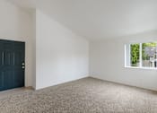 Thumbnail 5 of 36 - A room with a dark blue door and a window showing greenery outside.