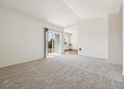 Thumbnail 39 of 74 - A large, empty room with a carpeted floor and a sliding glass door leading to a balcony.