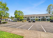 Thumbnail 6 of 35 - A parking lot in front of a building with cars parked.