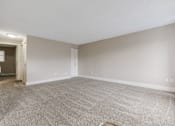 Thumbnail 11 of 31 - A large, empty room with carpeted flooring and white walls.