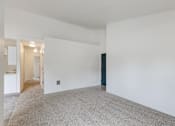 Thumbnail 6 of 36 - A large empty room with a carpeted floor and white walls.