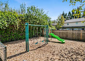 Thumbnail 7 of 35 - A playground with a green slide and a green monkey bars.