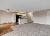 Thumbnail 12 of 31 - A spacious living room with a kitchen area in the background.