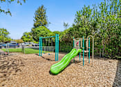 Thumbnail 8 of 35 - A playground with a green slide and a red swing set.