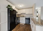Thumbnail 15 of 31 - A black fridge in a kitchen with white cabinets.