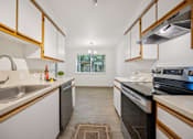 Thumbnail 5 of 37 - A modern kitchen with white cabinets and a black stove top oven.