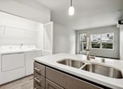 Thumbnail 17 of 46 - A modern kitchen with a white washing machine and a stainless steel sink.
